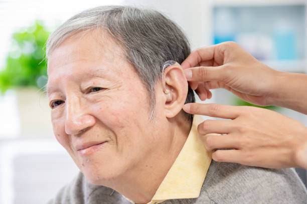 A senior using the B Klis Senior Hearing Aid comfortably during a family conversation.