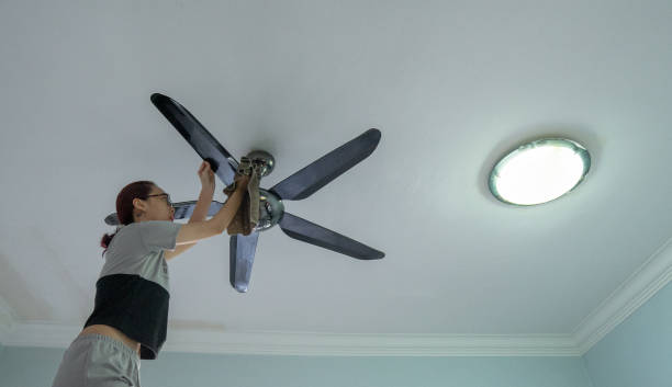 A person replacing the halogen light bulb in a Roto F ceiling fan.